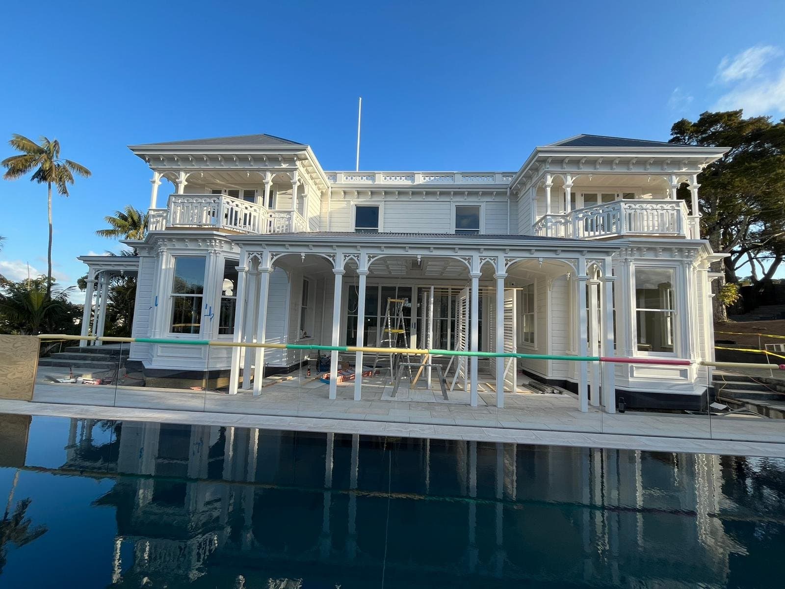 White two-storey villa repainted by Interior Drywall Worx, reflected in a swimming pool