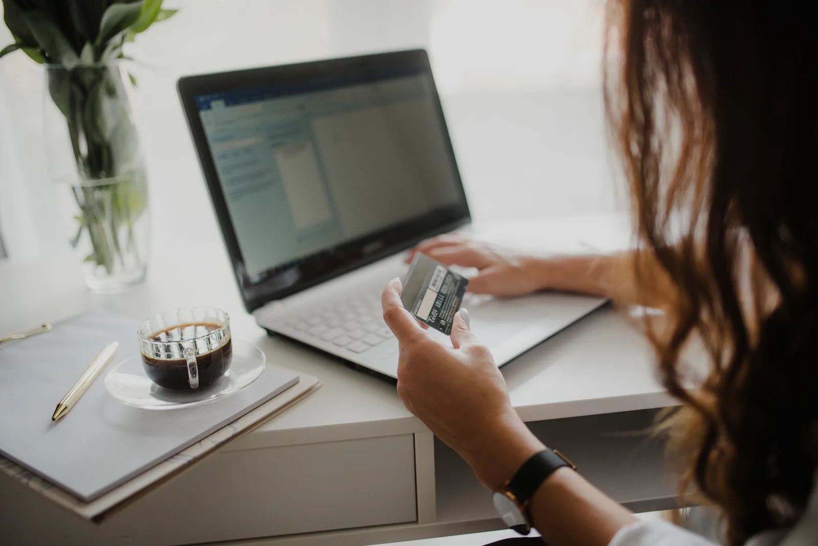 Shopper holding a credit card while buying from an online store on a laptop