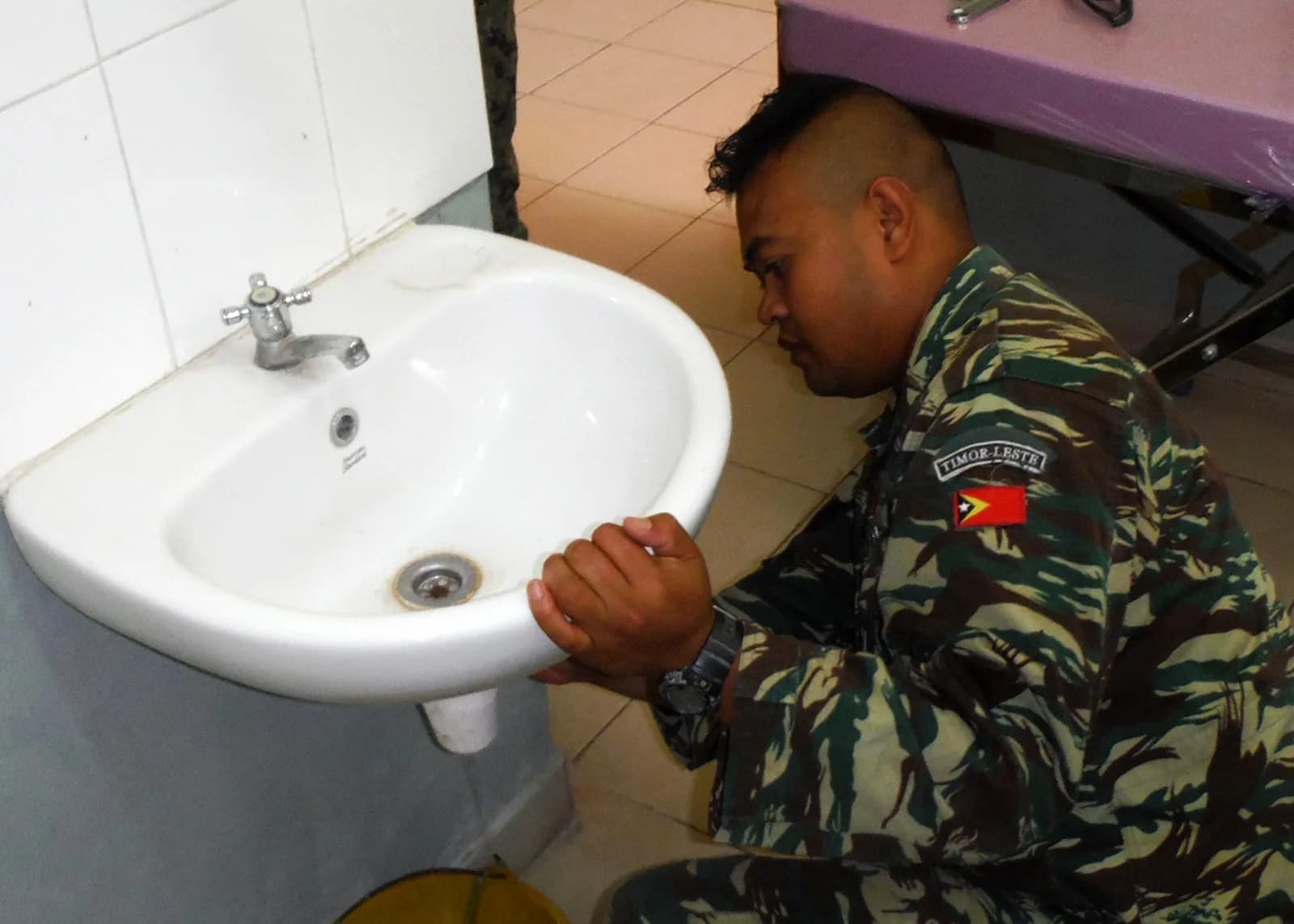 Plumber repairing pipework under a sink